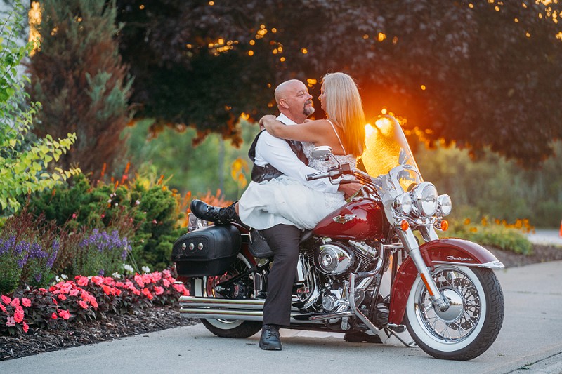 bride and groom on motorcycle at sunset